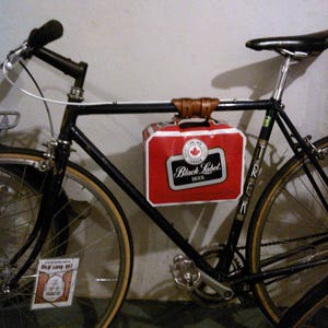 6-pack frame cinch used to hold a lunch box and attached to the top tube of a bicycle frame.