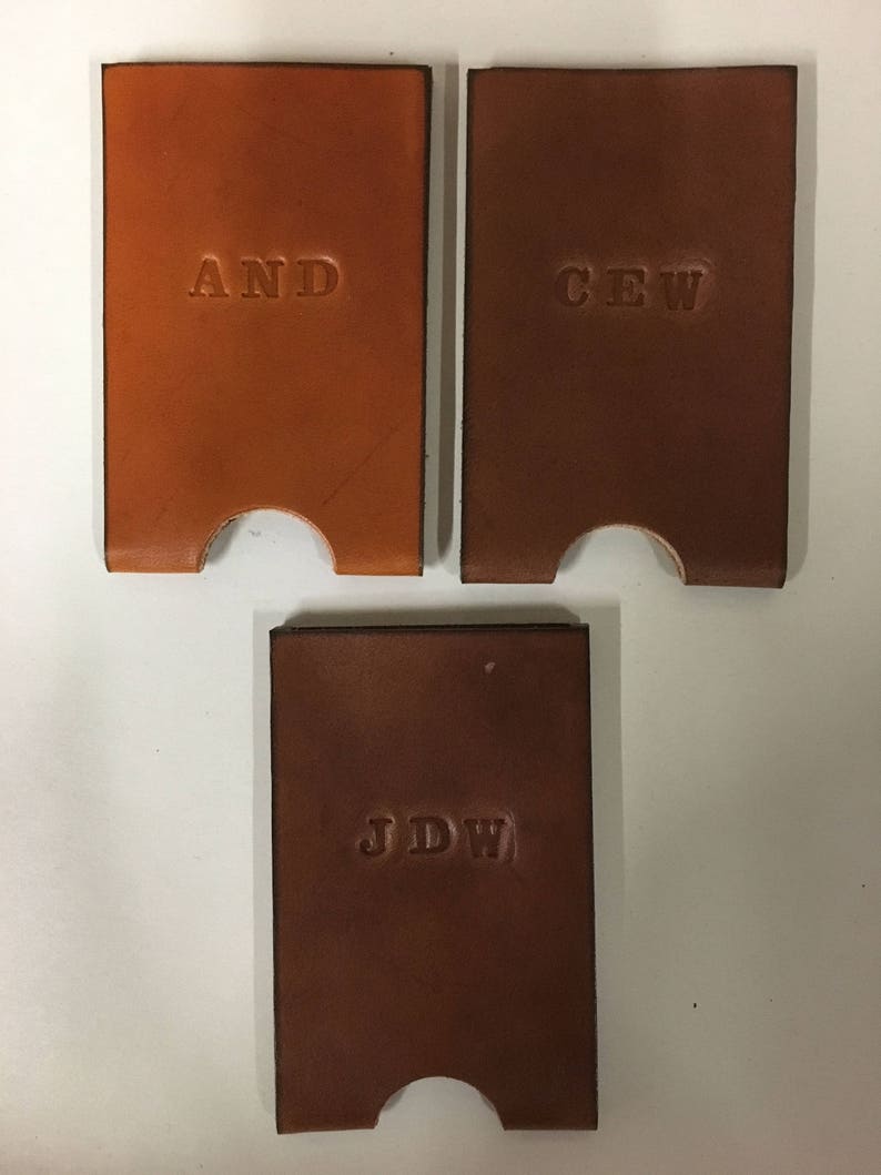 Three examples of monogramming shown clockwise: "AND" on honey leather and "CEW" and "JDW" on dark brown leather wallets