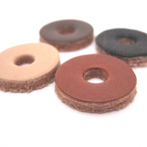 May include: Four leather rings in different colors: brown, beige, dark brown, and black. Each ring has a hole in the center.