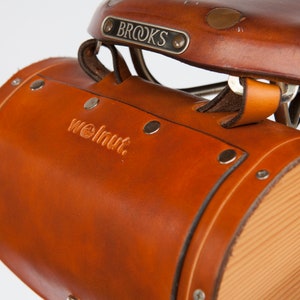 Close-up of honey leather barrel bag attached to seat tabs on Brooks saddle