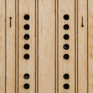 Close-up of laser etched birch playing surface on travel cribbage board, with pegging holes and directional arrows, and a different striping to differentiate the two tracks.