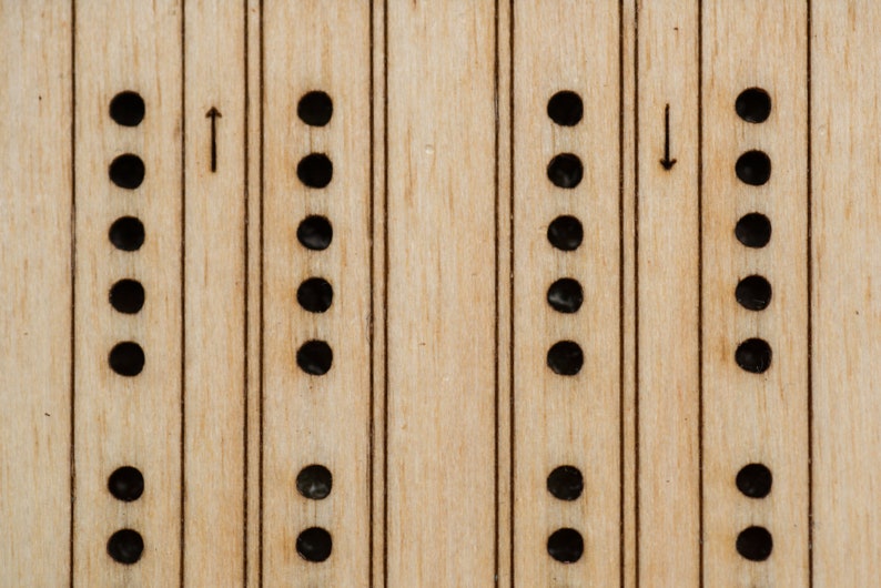 Close-up of laser etched birch playing surface on travel cribbage board, with pegging holes and directional arrows, and a different striping to differentiate the two tracks.