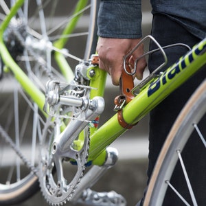 Close-up of person carrying green bike on down a flight of stairs using honey leather bike handle