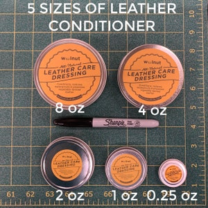 May include: Five different sizes of leather care dressing in metal tins. The tins are labeled "Walnut All-Natural Leather Care Dressing". The tins are arranged from largest to smallest, with the largest tin being 8 ounces and the smallest tin being 0.25 ounces.