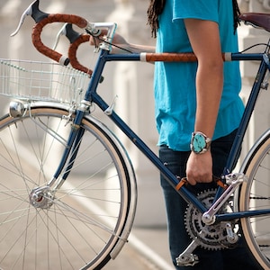 Person holding bike by leather handle installed between the down tube and seat tube