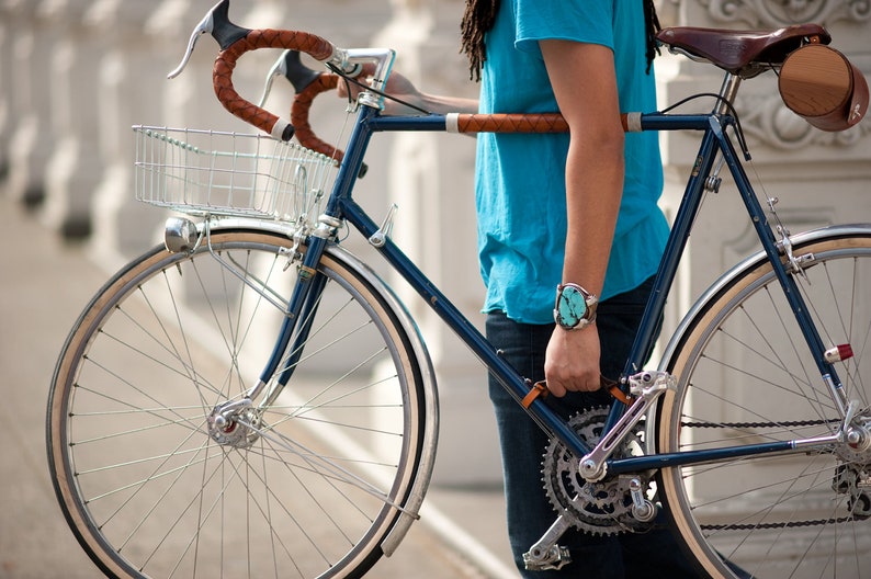 Person holding bike by leather handle installed between the down tube and seat tube