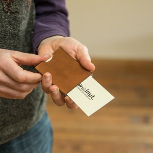 Woman demonstrating how to push cards out of leather business card wallet