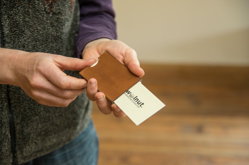 Woman demonstrating how to push cards out of leather business card wallet