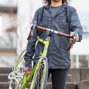 Person carrying green bike downstairs using the "little lifter" leather bike handle