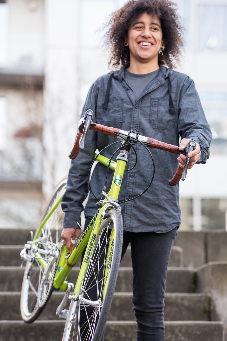 Person carrying green bike downstairs using the "little lifter" leather bike handle