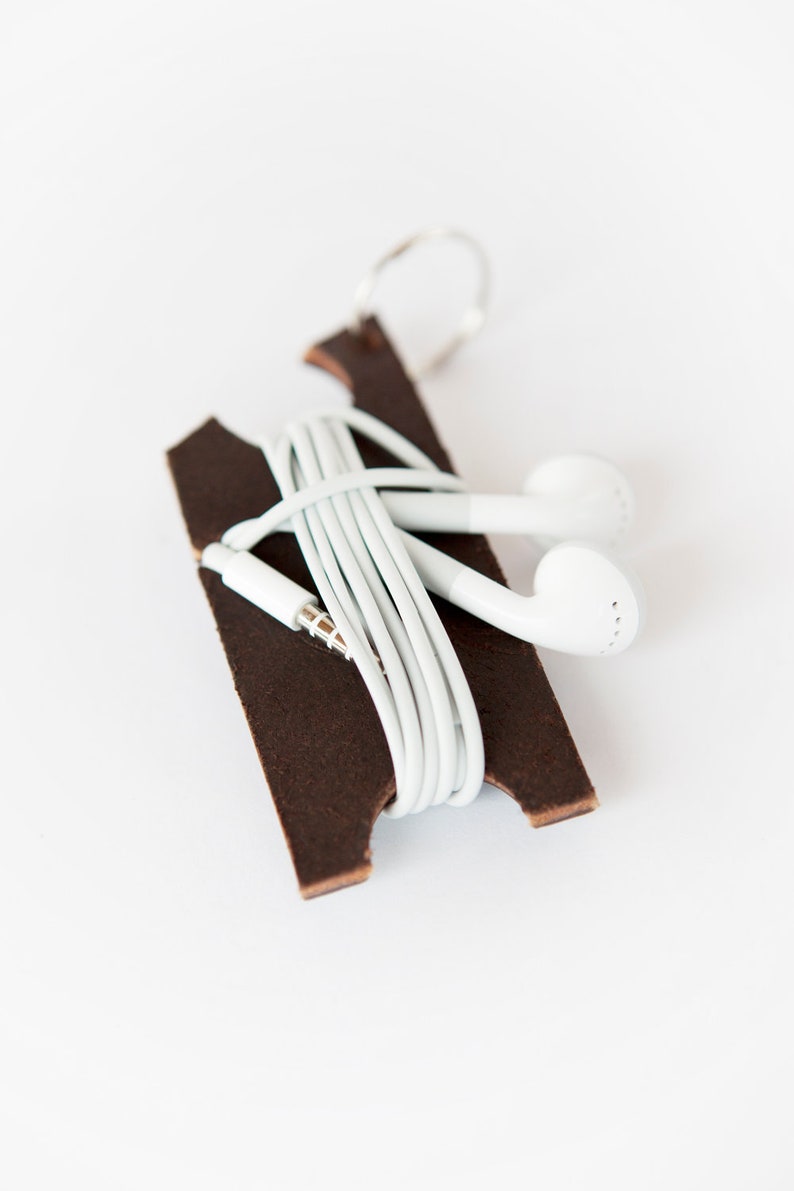 Dark brown leather earbud holder with white Apple headphones