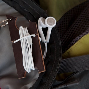 Dark brown leather keychain holder attached to the interior of a backpack with strap