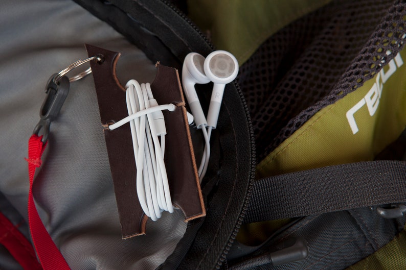 Dark brown leather keychain holder attached to the interior of a backpack with strap