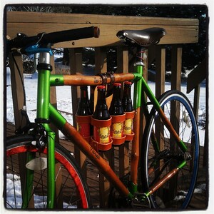 Customer photo of a Honey / Bamboo 6-pack held to the top tube of a bamboo Panda bicycle with a dark brown leather 6-pack carrier strap