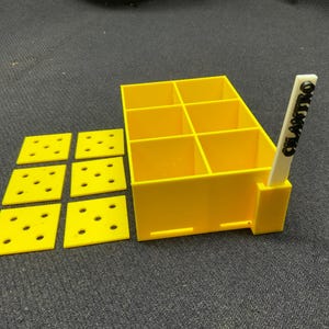 May include: A yellow, six-compartment organizer with six yellow square inserts. A white label with the word "CILANTRO" in black is inserted in the organizer. The items are on a dark surface.