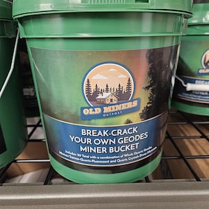 May include: A green plastic bucket with a label that reads "Old Miners Outpost Break-Crack Your Own Geodes Miner Bucket Includes: 20 Total with a combination of Whole Quartz Geodes, Mexican Trancos-Quartz-Fluorescent and Quartz Crystals-Druzy More"