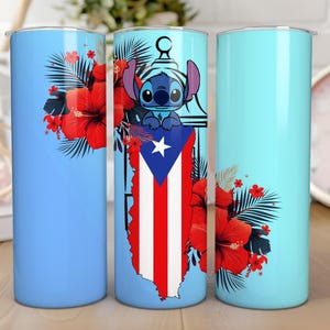 May include: A light blue tumbler featuring a design of Stitch, the Puerto Rican flag, and red hibiscus flowers. The tumbler has a cylindrical shape and is likely made of stainless steel. The design is repeated on the tumbler.