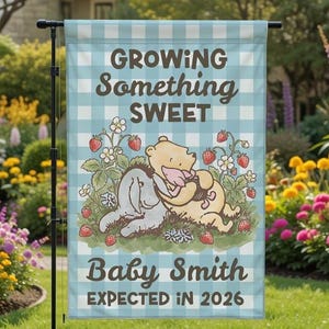 May include: A light blue and white gingham garden flag with the text "Growing Something Sweet" and "Baby Smith Expected in 2026." The flag features illustrations of Winnie the Pooh and Eeyore with strawberries.