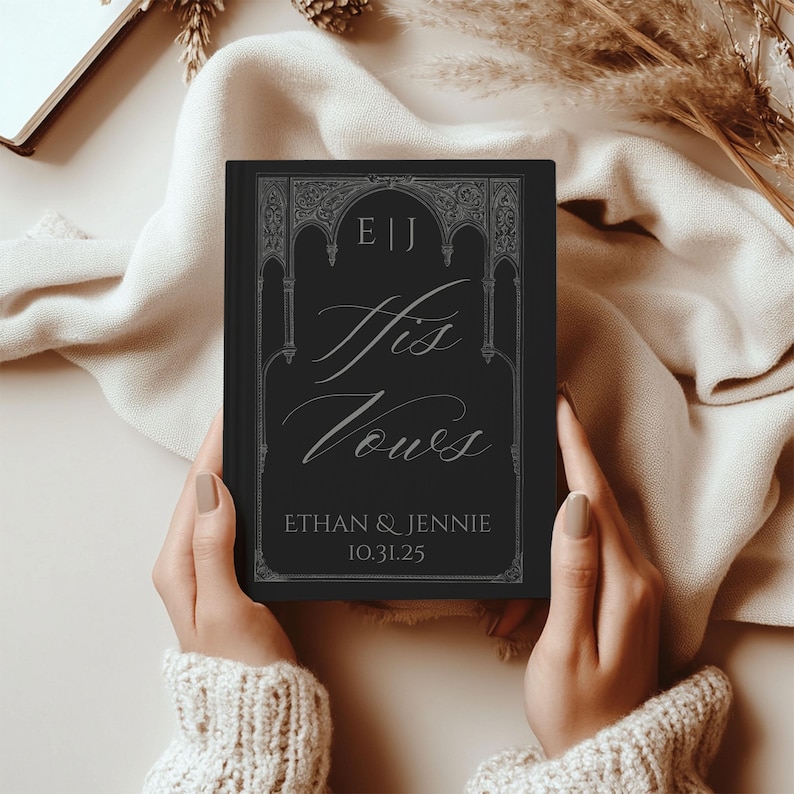 May include: A black book titled "His Vows" with silver lettering and decorative border. The book includes the initials "E|J", the names "Ethan & Jennie", and the date "10.31.25". The book is held by a person wearing a cream-colored sweater.