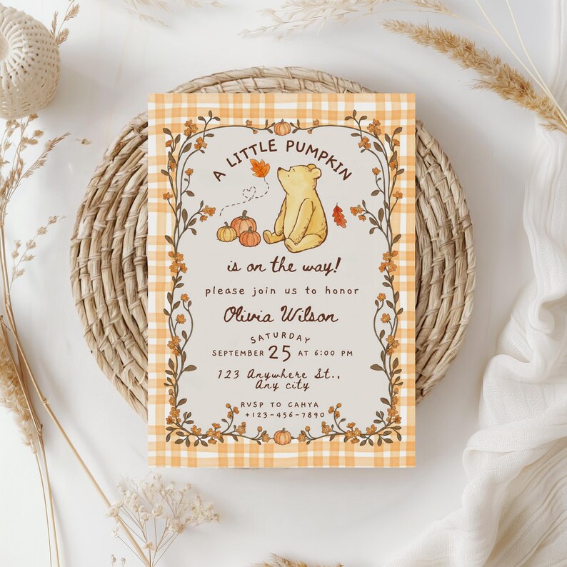 May include: A rectangular invitation card featuring a yellow bear illustration, orange pumpkins, and autumn leaves. The text reads A LITTLE PUMPKIN is on the way! please join us to honor Olivia Wilson SATURDAY SEPTEMBER 25 AT 6:00 PM 123 Anywhere St., Any city.