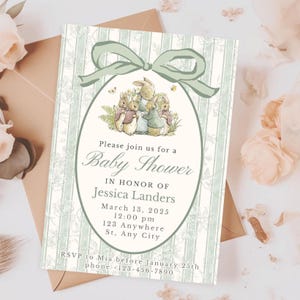 May include: Baby shower invitation with a bunny illustration inside an oval frame, adorned with a green bow. The invitation features text including the event details: "Please join us for a Baby Shower in honor of Jessica Landers."