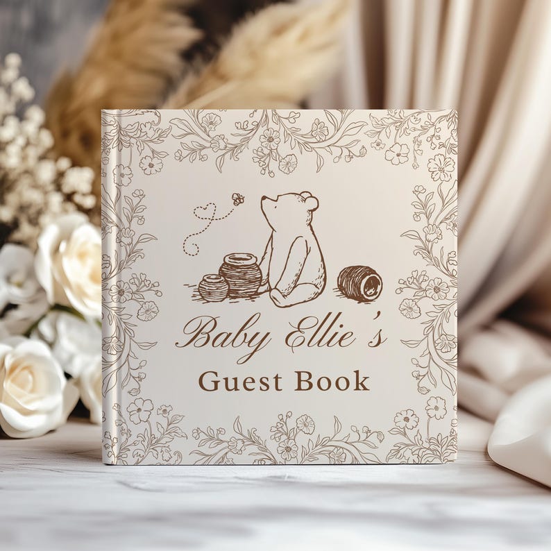 May include: A square guest book with a cream-colored cover featuring a brown line-art illustration of a bear sitting near honey pots and a bee. The text reads Baby Ellie's Guest Book, surrounded by a delicate floral border in brown ink.