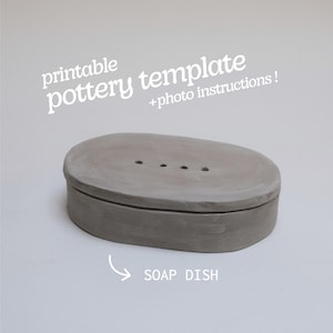 Puede incluir: Un jabonera gris de forma ovalada con tres orificios de drenaje. La jabonera está hecha de un material mate y tiene una tapa a juego. El texto en la imagen dice "printable pottery template + photo instructions!" y "SOAP DISH".