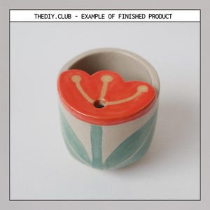 May include: A small, ceramic planter with a tulip design. The planter is beige with green leaves and a red tulip-shaped lid. The text "THEDIY.CLUB - EXAMPLE OF FINISHED PRODUCT" is at the top.