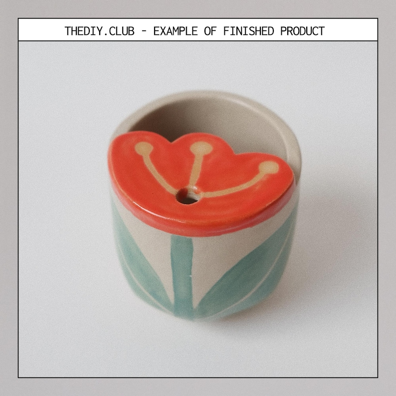 May include: A small, ceramic planter with a tulip design. The planter is beige with green leaves and a red tulip-shaped lid. The text "THEDIY.CLUB - EXAMPLE OF FINISHED PRODUCT" is at the top.
