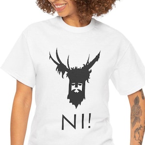Könnte beinhalten: Weißes T-Shirt mit einer schwarzen Grafik einer bärtigen Figur mit Geweih und dem Wort "NI!" darunter. Das T-Shirt besteht aus einem weichen Material und hat kurze Ärmel.