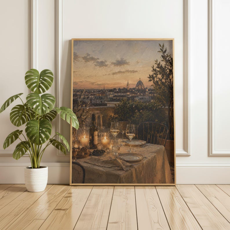 Pode incluir: Uma impress&atilde;o de arte de parede emoldurada retratando uma cena de jantar em um terra&ccedil;o ao p&ocirc;r do sol, com uma mesa posta com ta&ccedil;as de vinho, uma garrafa e velas, com vista para uma paisagem urbana com uma c&uacute;pula sob um c&eacute;u dourado.