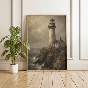 May include: A framed wall art print depicting a tall, weathered lighthouse standing on a dark, craggy cliffside overlooking a turbulent ocean with crashing waves under a cloudy, muted sky, presented in a simple, light-toned wooden frame.