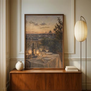 Pode incluir: Uma impress&atilde;o de arte de parede retangular emoldurada retratando uma vista do p&ocirc;r do sol sobre o horizonte de uma cidade com a c&uacute;pula de uma catedral. O primeiro plano mostra uma mesa posta para jantar com ta&ccedil;as de vinho, garrafa e velas.