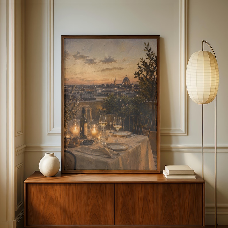 Pode incluir: Uma impress&atilde;o de arte de parede retangular emoldurada retratando uma vista do p&ocirc;r do sol sobre o horizonte de uma cidade com a c&uacute;pula de uma catedral. O primeiro plano mostra uma mesa posta para jantar com ta&ccedil;as de vinho, garrafa e velas.