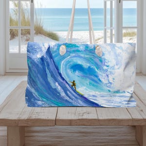 May include: A rectangular tote bag featuring a vibrant, painterly depiction of a large, curling ocean wave in shades of deep blue, turquoise, and white. A small figure on a yellow surfboard is positioned on the face of the wave.