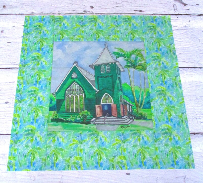 May include: A watercolor painting of a green church with a tall steeple and a palm tree in front. The church is surrounded by lush green foliage and a blue sky with white clouds. The painting is framed with a border of green and blue palm leaves.