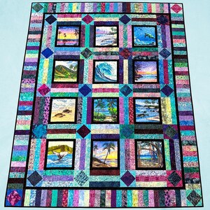 May include: A rectangular quilt featuring twelve square panels with tropical beach and ocean scenes, including palm trees, sea turtles, a whale tail, and waves. The panels are framed by a colorful border of multi-colored fabric strips.