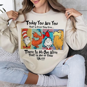 May include: Beige sweatshirt featuring four colorful Dr. Seuss characters. The text on the sweatshirt reads "Today You Are You that is truer than true... There Is No One Alive that is you er than YOU!!!"