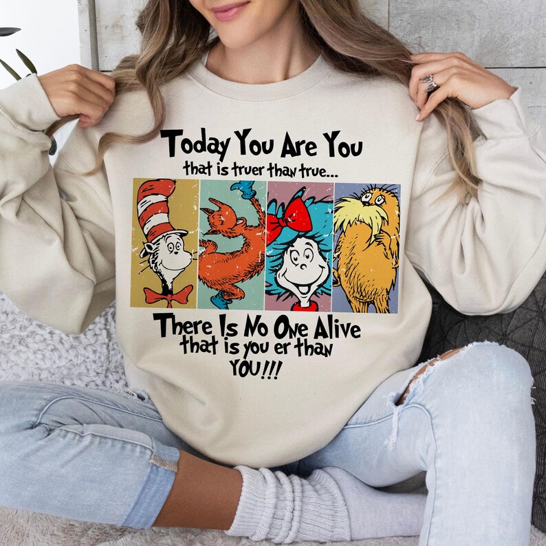 May include: Beige sweatshirt featuring four colorful Dr. Seuss characters. The text on the sweatshirt reads "Today You Are You that is truer than true... There Is No One Alive that is you er than YOU!!!"