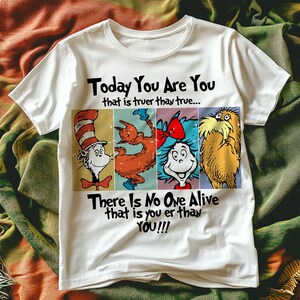 May include: White t-shirt featuring four cartoon characters in a rectangular design. The text "Today You Are You that is truer than true... There Is No One Alive that is you er than YOU!!!" is printed above and below the characters.