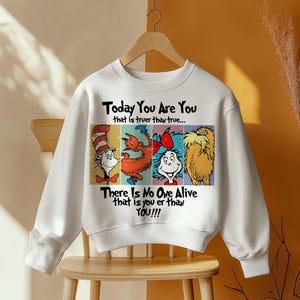 May include: White sweatshirt featuring four colorful cartoon characters and the text "Today You Are You" and "There Is No One Alive that is you er than YOU!!!". The design is printed on the front of the crew neck sweatshirt.