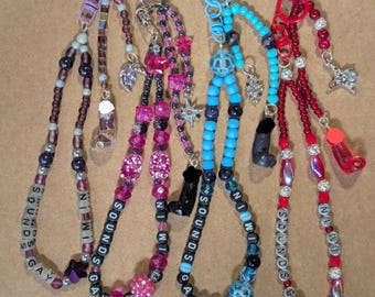 May include: Four beaded keychains with various colors and charms. Each keychain has the phrase "SOUNDS GAY" spelled out in white letter beads. Charms include stars, boots, and other decorative elements. The keychains have different colored clasps.
