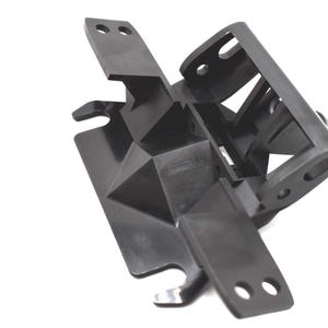 May include: A black, geometric plastic component with multiple arms and mounting holes. The object has a complex, angular design with a series of intersecting planes and a textured surface. The component appears to be a structural part.