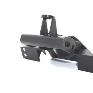 May include: A black, angular mechanical part with a cylindrical body and various mounting points. The part has a matte finish and is set against a white background, highlighting its geometric design and structural features.