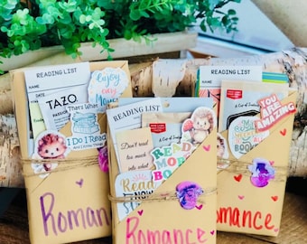 May include: Three brown paper packages wrapped in a decorative style with the word "Romance" written on each. Each package is decorated with stickers, including a hedgehog, a book, and a heart. The packages are sitting on a wooden surface.