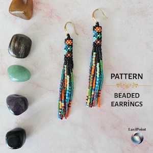 May include: Pattern beaded earrings with a black base and colorful beads in orange, blue, green, and red. The earrings have gold-colored hooks and are displayed with various polished stones on a light pink surface.