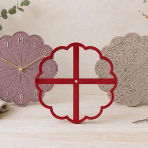 May include: A mauve scalloped wall clock with gold hands and white numbers, a red four-sectioned circular frame, and a grey scalloped disc featuring an embossed floral pattern. The items are arranged together, showcasing distinct textures and designs.