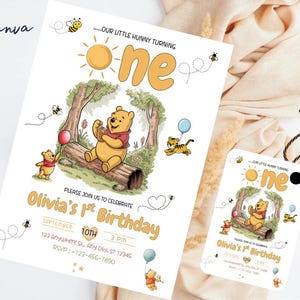 Puede incluir: Una invitación de cumpleaños y una etiqueta con el tema de Winnie the Pooh. La invitación presenta una ilustración de dibujos animados de Winnie the Pooh, un tigre y un globo. El texto dice "Olivia's 1st Birthday" e incluye detalles del evento.