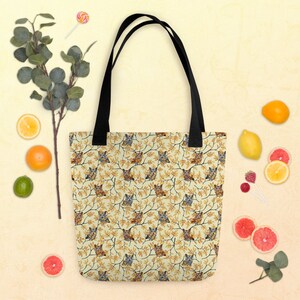 May include: A tote bag with black handles and a repeating pattern of brown and gray owls perched on yellow-leafed branches against a light cream background. The bag features a rectangular shape with a flat bottom and two sturdy shoulder straps.