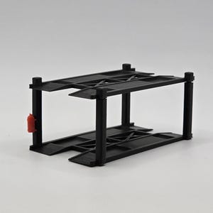 May include: Black metal two-tier car parking garage model. The garage has a red fire extinguisher on the side.